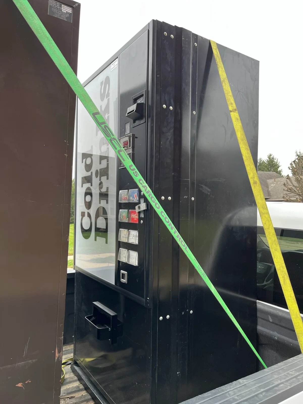 An old vending machine strapped down for scrap metal pickup -- mostly metal by weight, so it qualifies for the $11 base fee