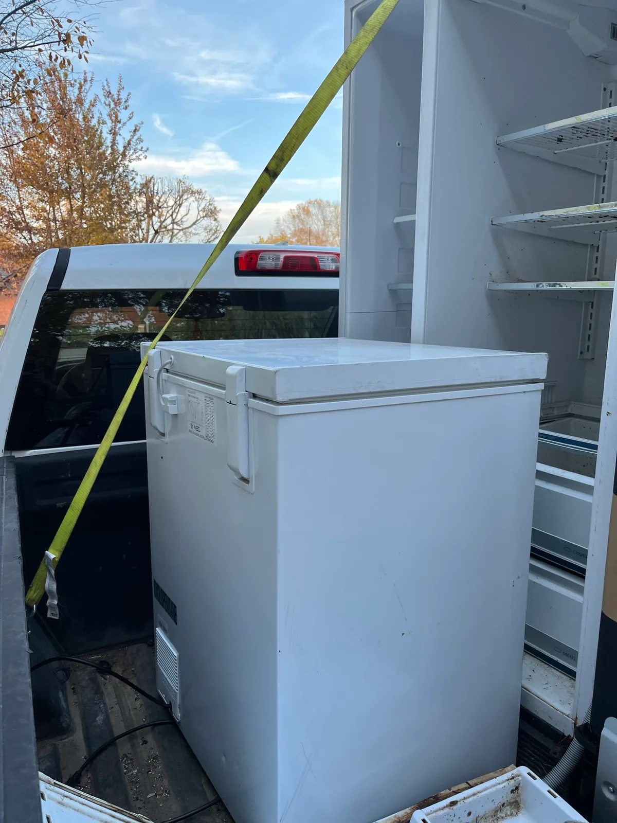 Chest freezer strapped inside a box truck, headed to the recycling yard for certified freon recovery