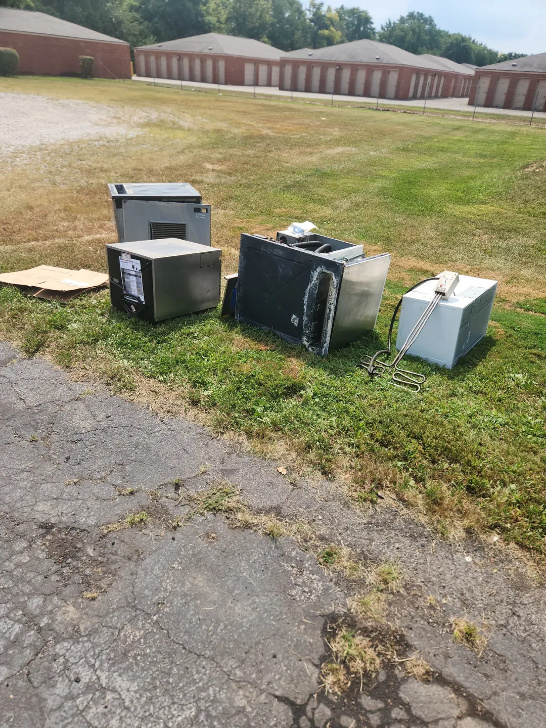 Used stainless units and metal appliances staged outdoors for pickup -- the scrap value that piles up in garages and basements