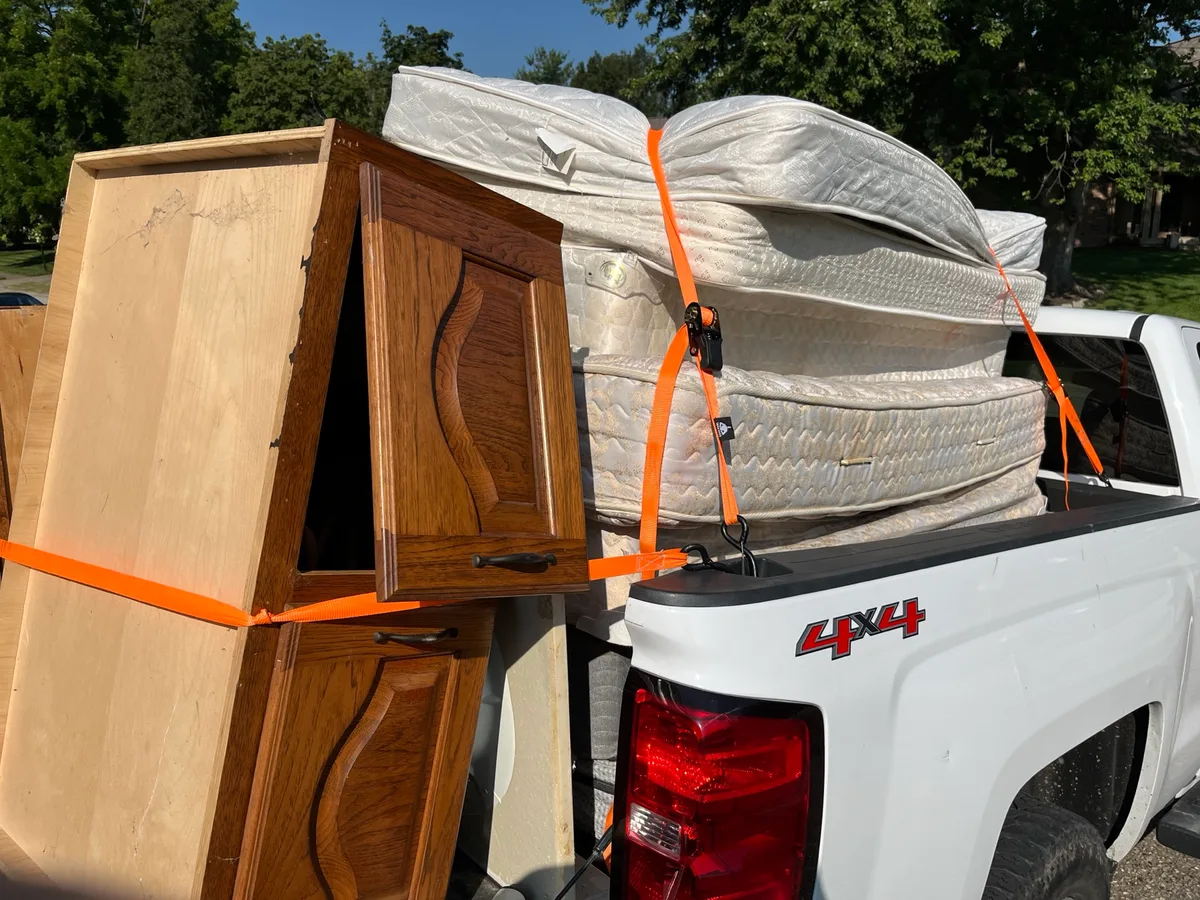 Wooden cabinet units and stacked mattresses strapped into a pickup truck after a furniture removal stop on the south side of Indianapolis