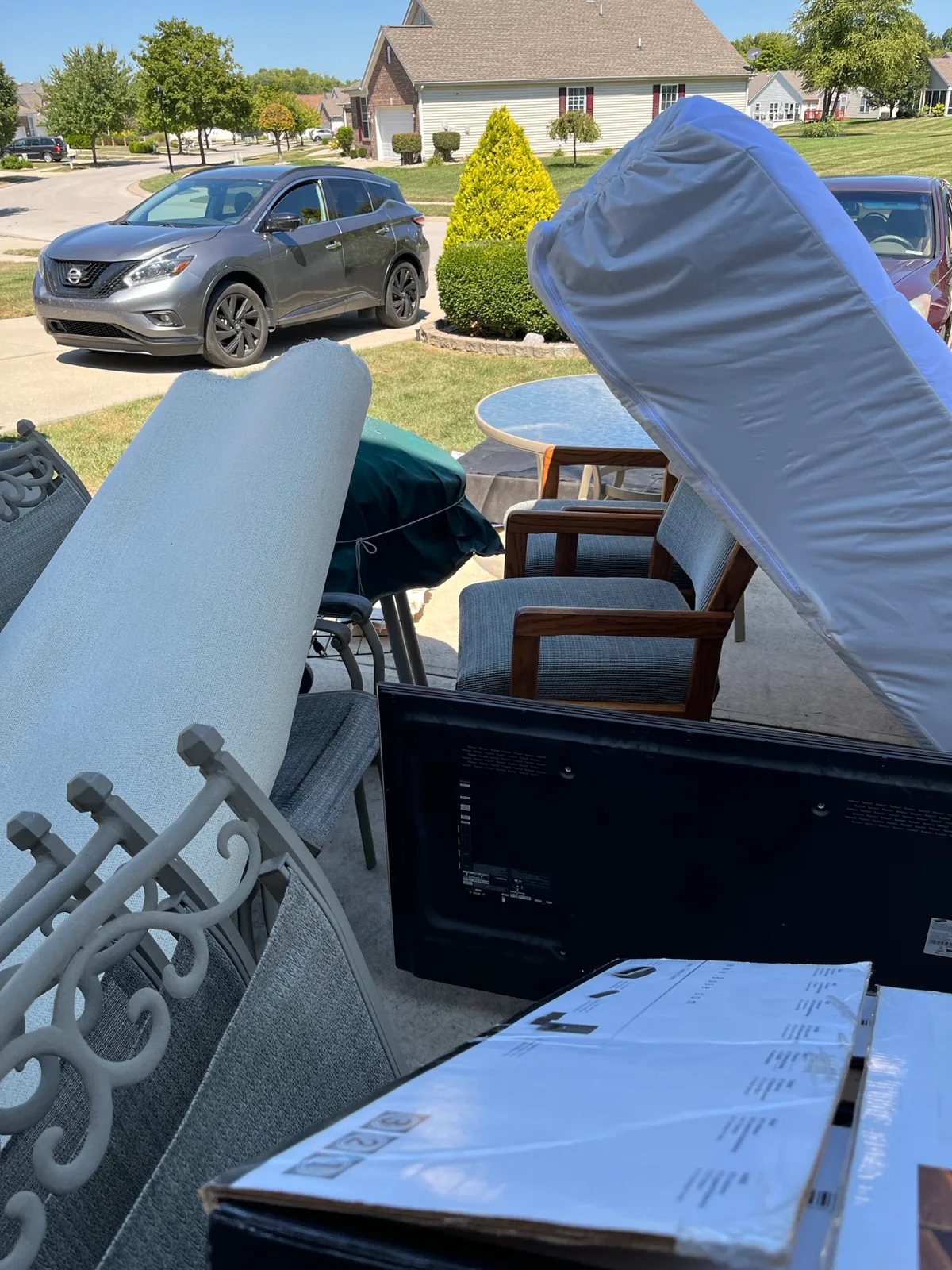 Household items including a white mattress, a TV, and patio furniture staged outside an Indianapolis home for pickup