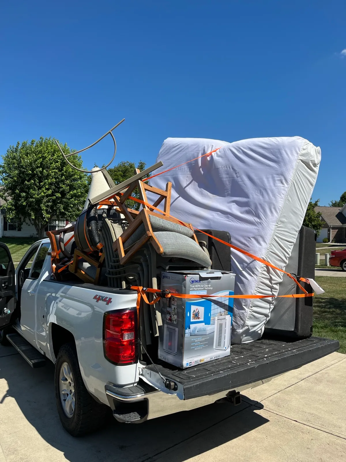 Stacked patio chairs and household items loaded in a pickup truck bed after an Indianapolis furniture removal stop